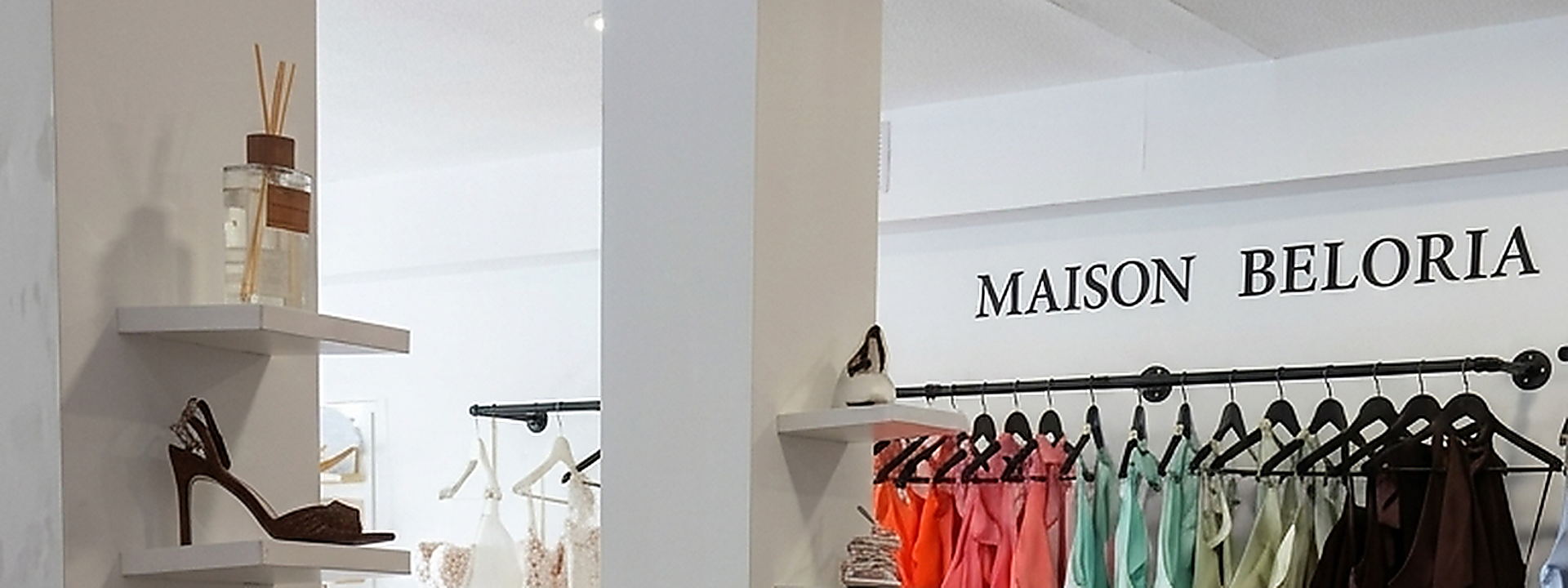 Portant de robes de cérémonie colorées et présentoir d’accessoires dans la boutique Maison Beloria